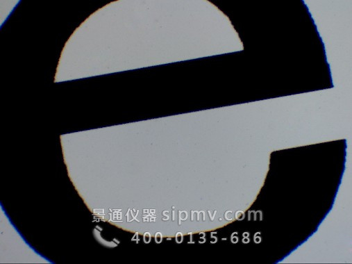 显微镜下的字母e装片. 字母边缘有颜色，由物镜的色差引起的